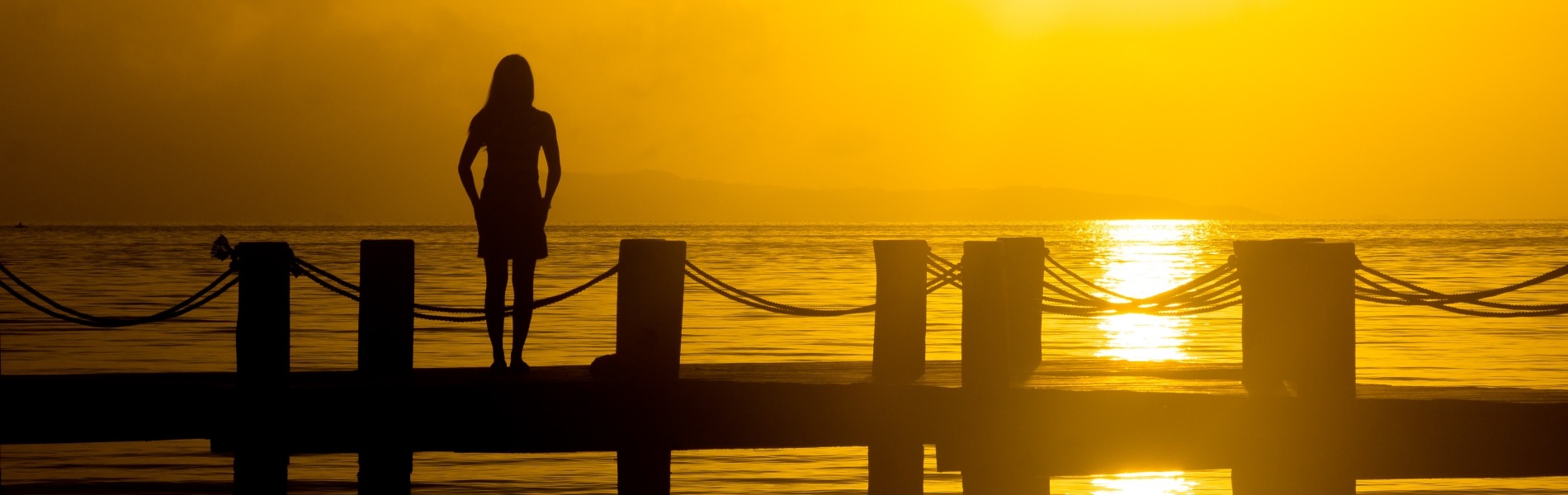 Image of a woman on a jetty with a sunset